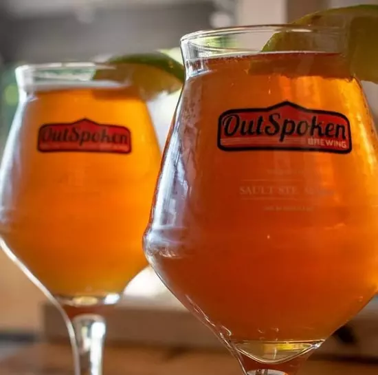 Deux verres de la même bière, garnis de quartiers de lime. L'un au premier plan et l'autre au second plan